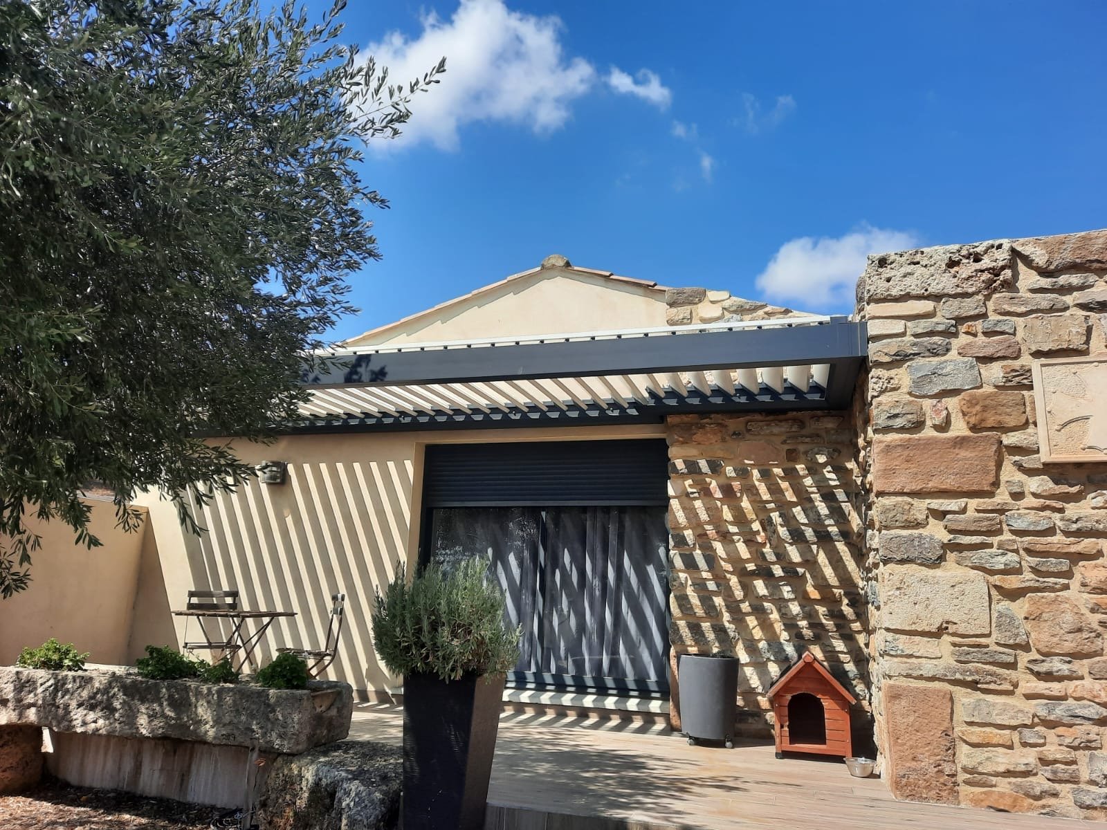 Pergola bioclimatique moderne gris lame blanche sur mur pierre